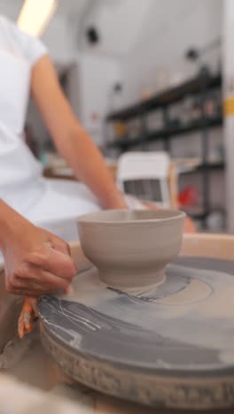 hands crafting a clay bowl on a pottery wheel