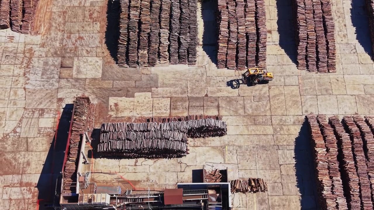 Wood stacks arranged in lines at a lumber yard during daylight