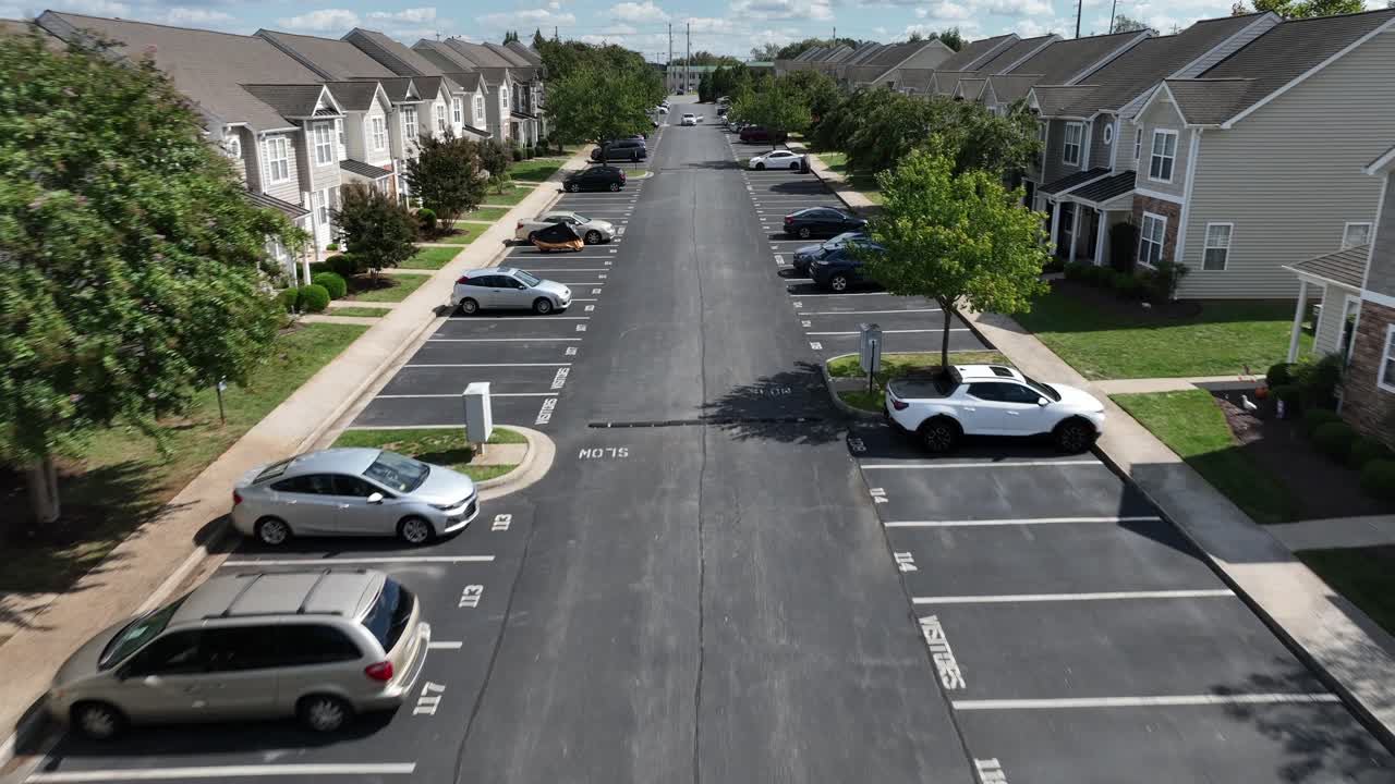 Aerial approaching flight over street with parking cars in suburb neighborhood. American suburb area in. summer season, Modern row of townhouses with porch and small front yard.Virginia, United States