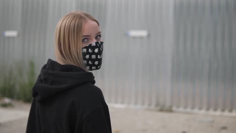 slow motion, blonde girl with face mask and hoodie looking at camera