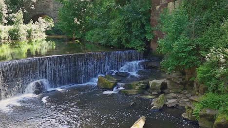 small waterfall with stone arched bridge in the background