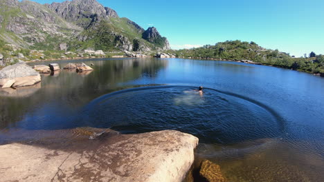 millennial young man with run on rock pier and jump into refreshing cool water of mountain forest lake festvagtinden