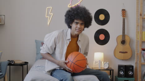 teenager with basketball in bedroom