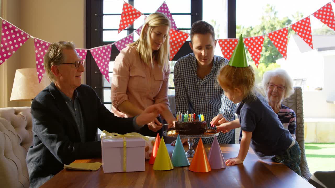 familia decorando pastel de cumpleaños en la sala de estar 4k