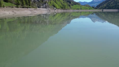 Superficie-De-La-Cuenca-De-Un-Lago-Con-Montañas-Reflejándose-En-El-Agua