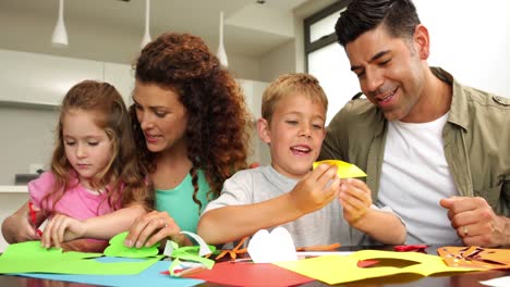 padres lindos y niños haciendo artes y artesanías en la mesa de la cocina
