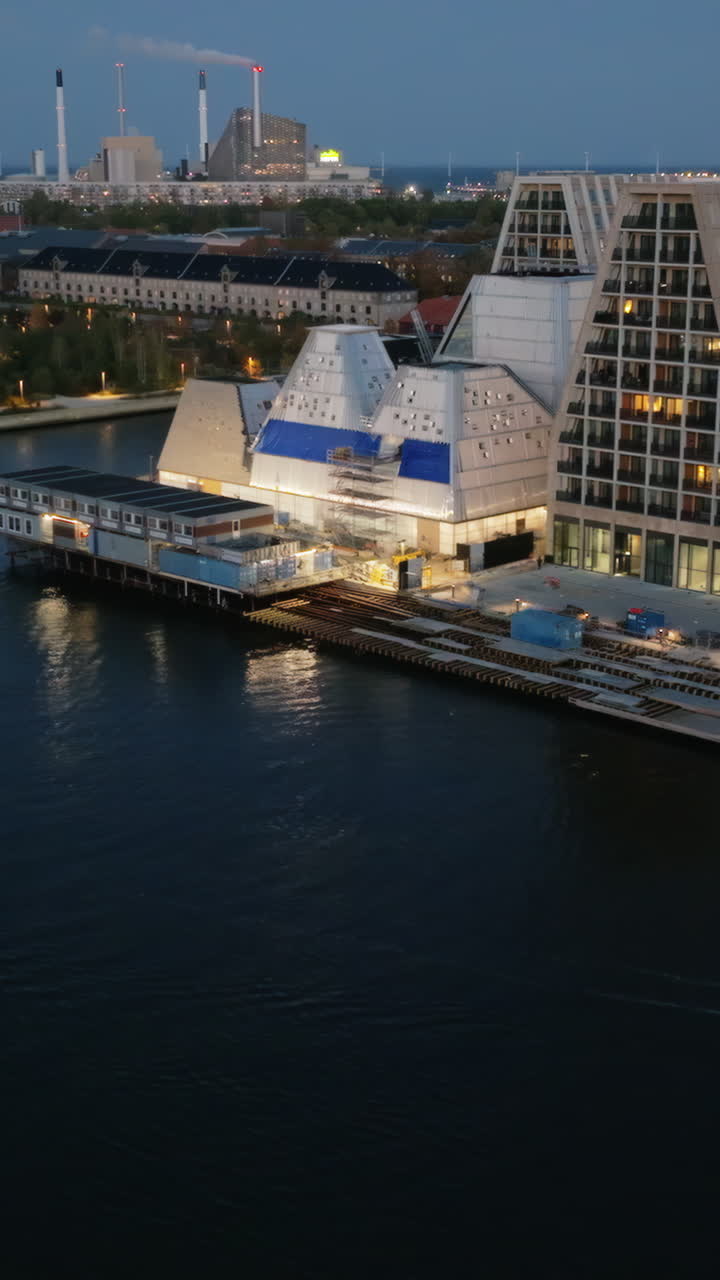 Aerial drone view of the Paper Island urban oasis surrounded by water in Copenhagen, Denmark at night. Vertical