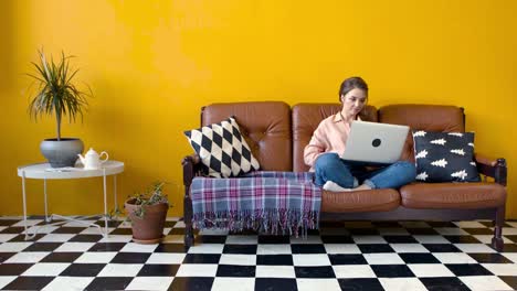 mujer trabajando en una computadora portátil en un sofá en una acogedora sala de estar
