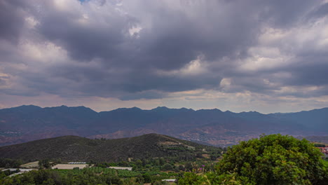 Timelapse-shot-of-dark-clouds-passing-over-green-mountain-range-on-an-overcast-day