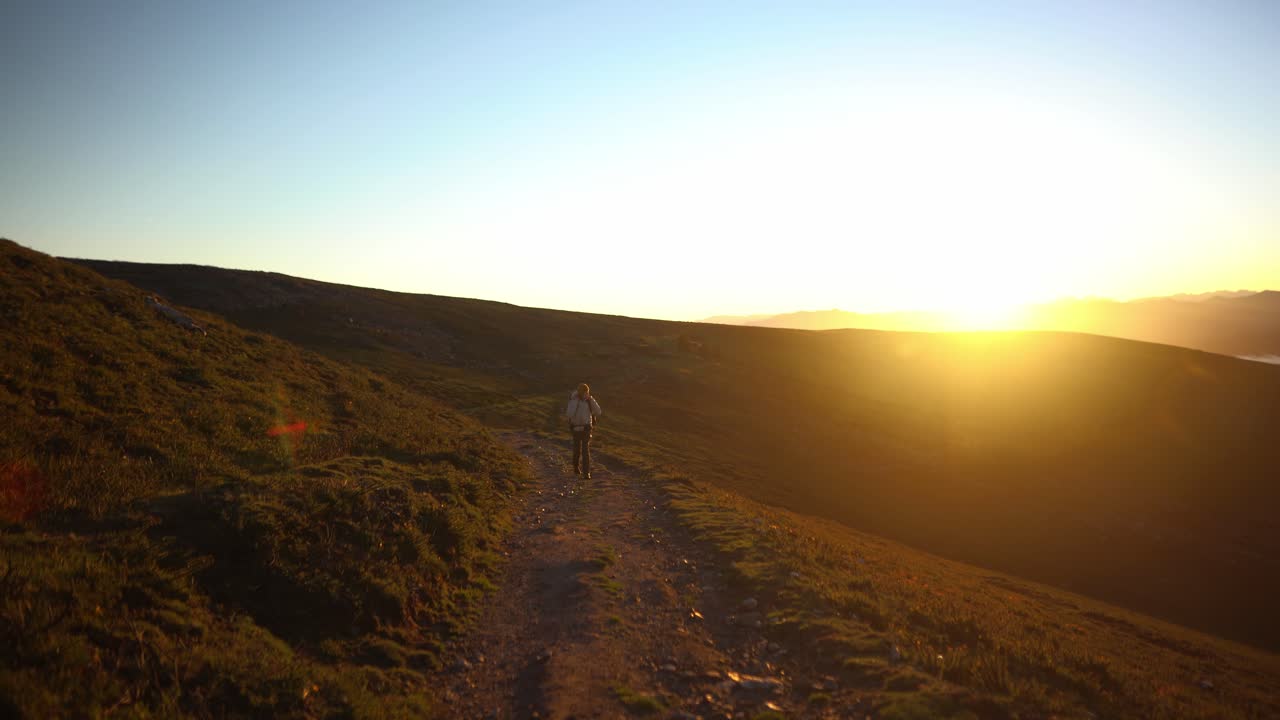hombre de mochila amanecer sol caminando en la naturaleza desierto sin árboles