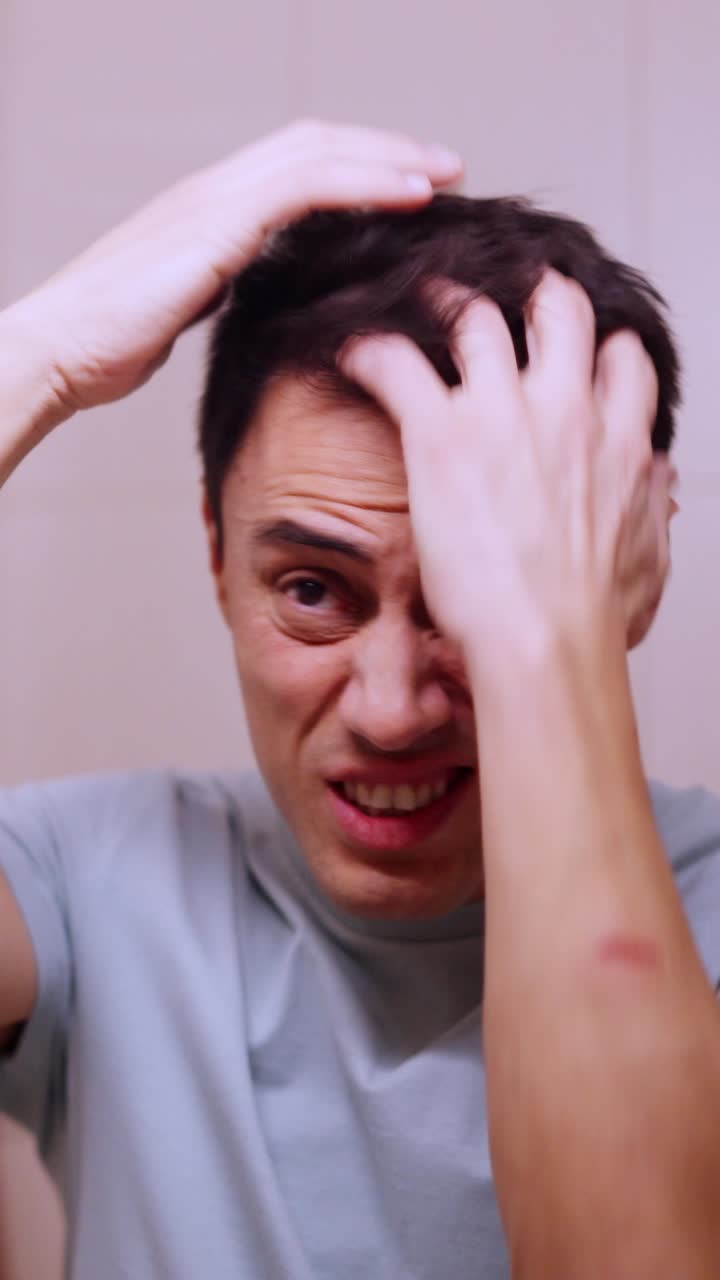 Insecure man combing hair before a date in bathroom mirror