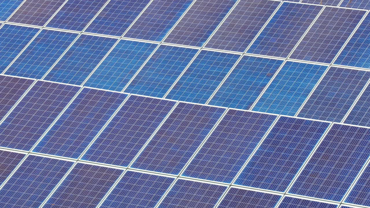 Zoom cinematografico lento su numerosi pannelli fotovoltaici in un grande impianto solare di energia verde.