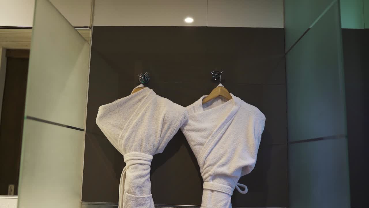 Pair of white robes hang in luxurious sauna room of exclusive hotel suite. Argentina.