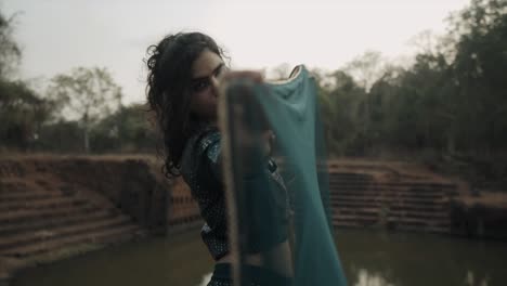 a model with expertise in makeup artistry, adorned with exquisite accessories, and hairstyle, gazes directly ahead while elegantly dressed in an indian attire, gracefully holding a burqa