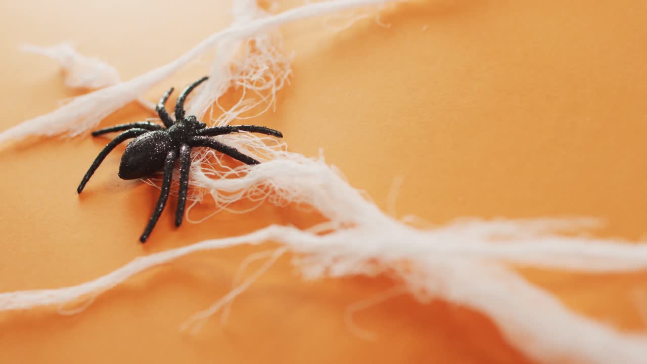 primer plano de un juguete de araña que forma una tela de araña contra un fondo naranja