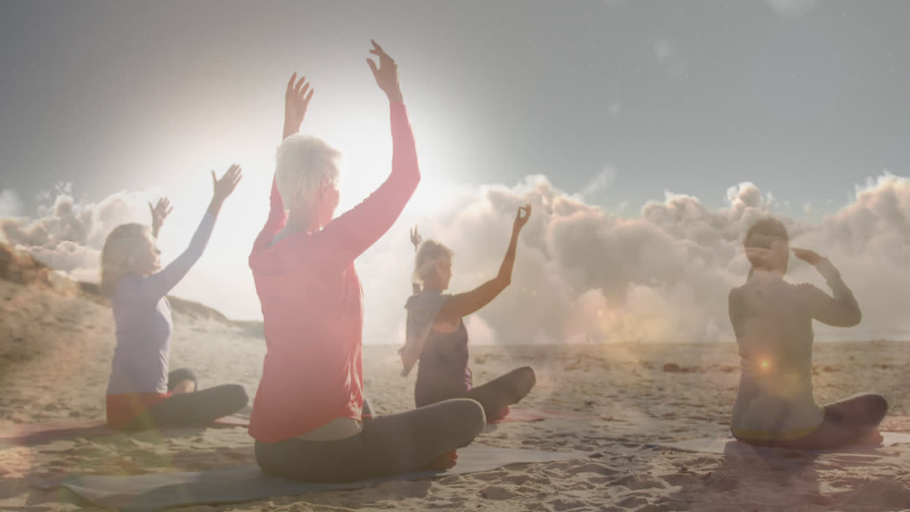 Animation of glowing light over happy senior women practicing yoga by seaside