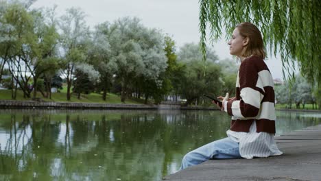 woman relaxing by a pond in a park