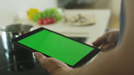 man is using tablet pc at kitchen in portrait mode