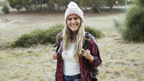 feliz chica de trekking con sombrero de lana posando al aire libre