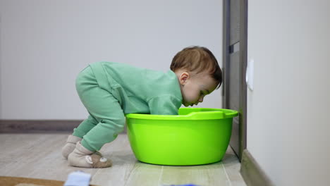 baby playing with a plastic basin