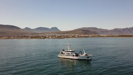 Marine-research-vessel-drifting-off-the-coast-with-mountains-in-the-back-on-a-calm-day