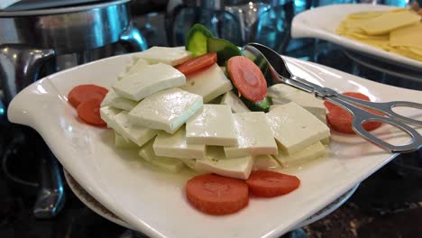 plate of sliced feta cheese and vegetables at a buffet