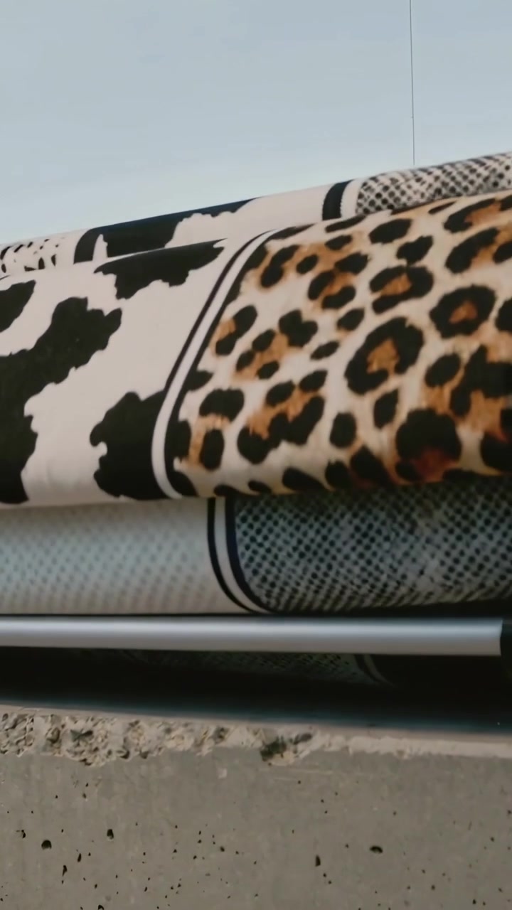 Video vertical: Cámara moviéndose revelando telas enrolladas en el alféizar del tejado sobre una barra, mostrando manchas de leopardo.