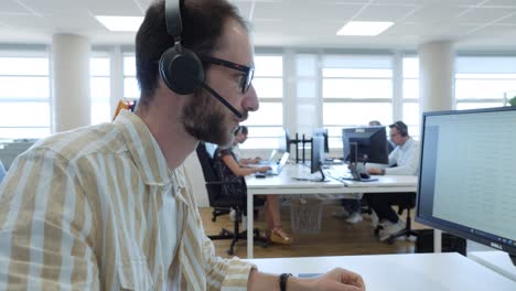 man putting on and using headphones while working at a computer in an office