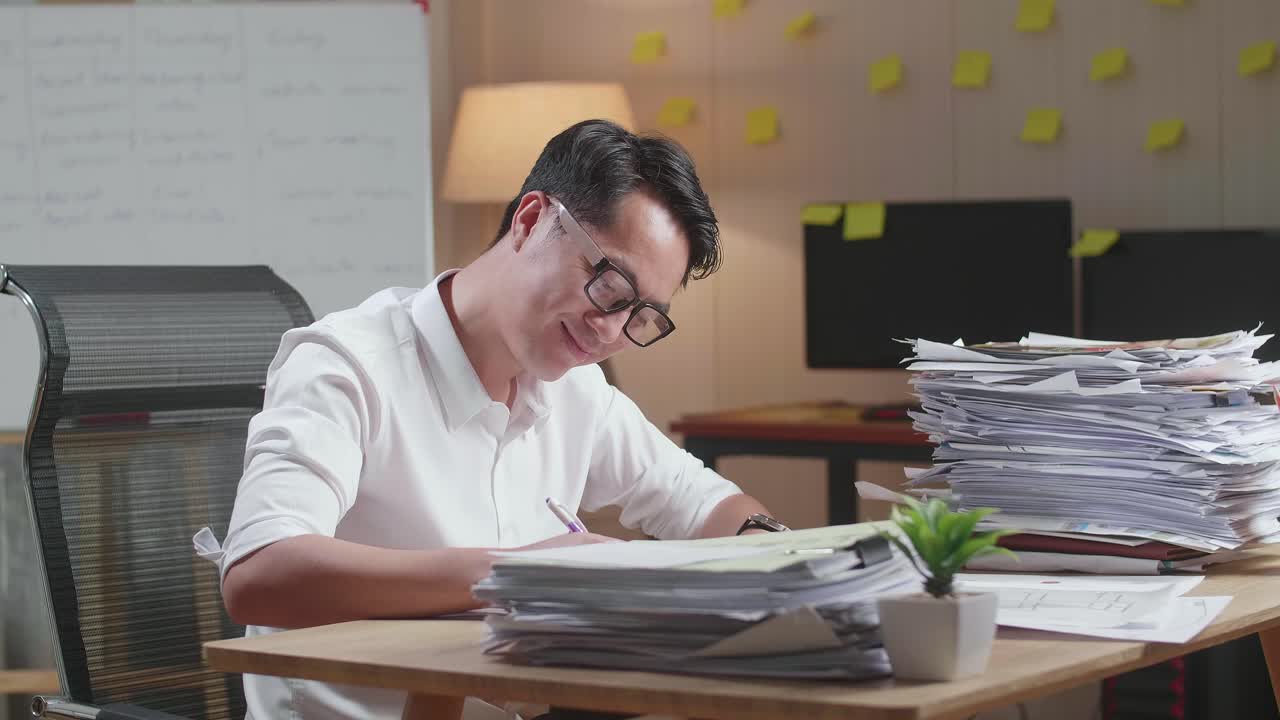 Smiling Asian Man Enjoys Working With Documents At The Office