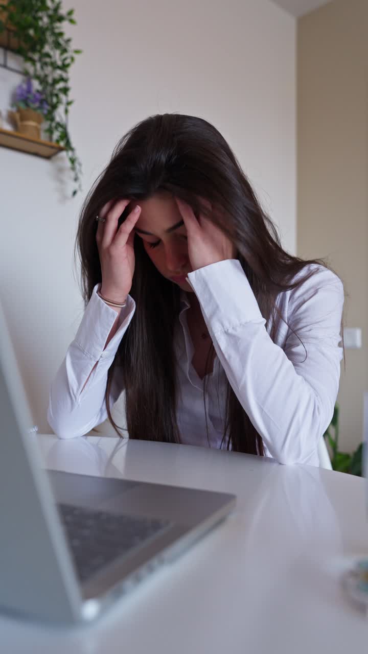 Giovane donna frustrata che lavora al laptop alla scrivania dell'home office