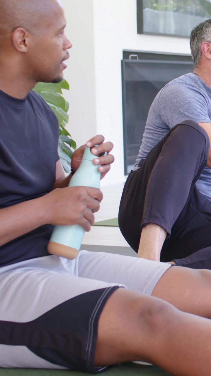 Vertical video: Starting session, man 40s talking, guiding stretch at home, blue tee, teal bottle