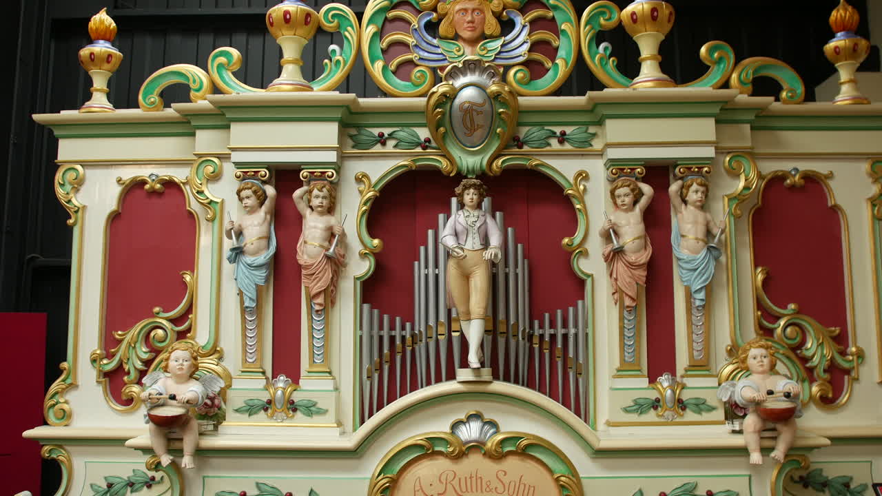 An organ with ornate wooden carvings and painted statues is standing as a decorative centerpiece. Antique pipe organ with cherubs and classical detailing is prominently featured