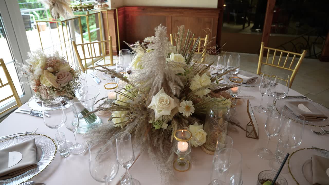 Fascinerende nærbilde av et elegant bryllupsbord, med et slående blomsterarrangement med hvite roser og delikate stearinlys. Myk belysning skaper en romantisk atmosfære.