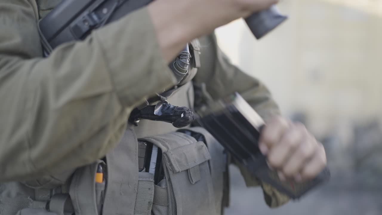 Closeup of an Israeli military soldier loading machine gun, Israel-Hamas war conflict, West Bank