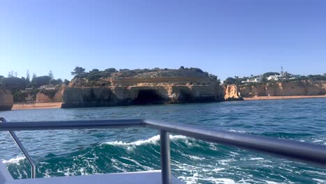 Boat-Sailing-Across-Sea-With-Coast-Hills-In-The-Distance