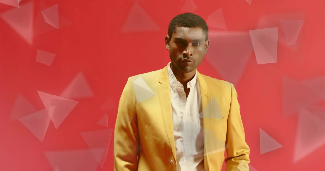 Modella di moda che sposta lo sguardo e ruota il busto, mostrando un completo giallo tra triangoli su uno sfondo rosso.