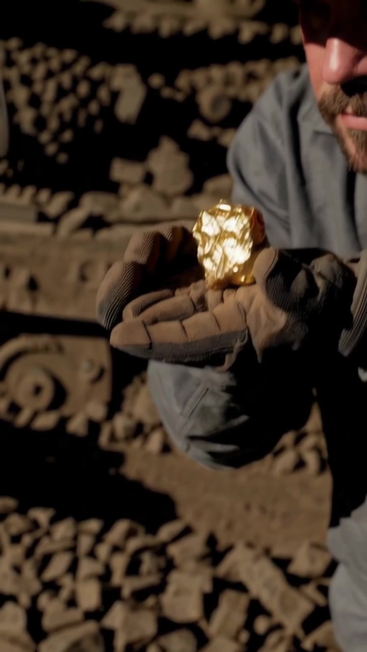 Minatori al lavoro in un cantiere polveroso che scoprono una pepita d'oro