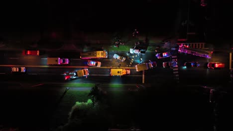 aerial top down of car accident on road at night. fire truck, police car and ambulance on street. american suburb district in virginia, usa.