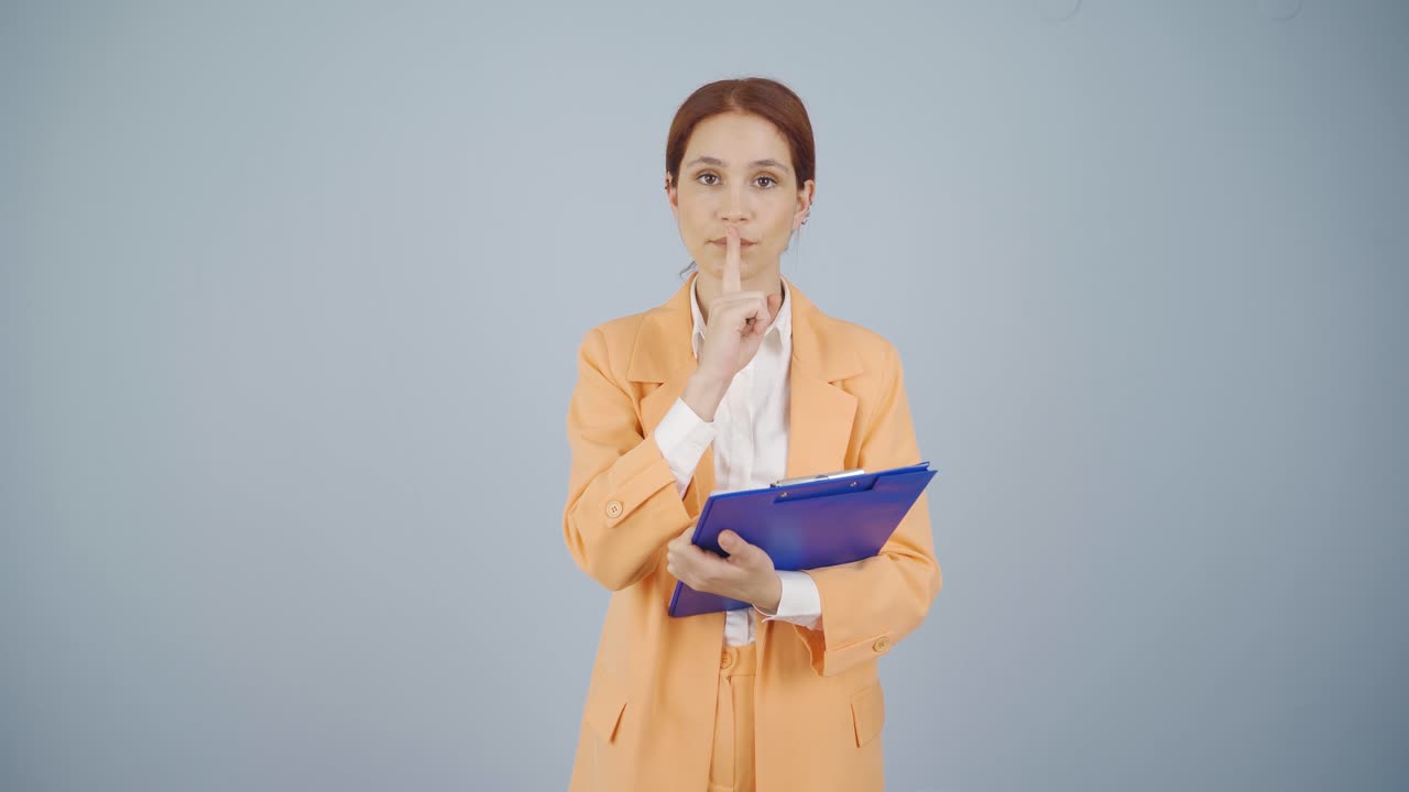 mujer de negocios diciendo cállate a la cámara.