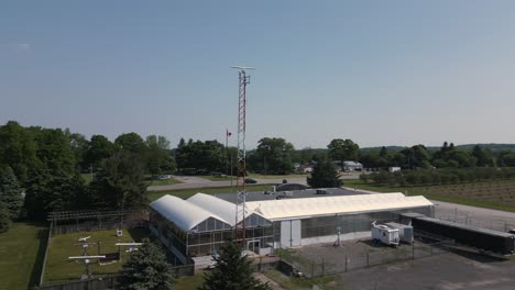 a drone flying around a security tower which is located in a rural country area with farms and a few roads around