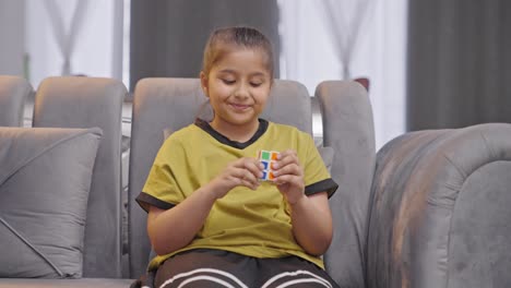 Happy-Indian-girl-kid-solving-a-Rubik's-cube