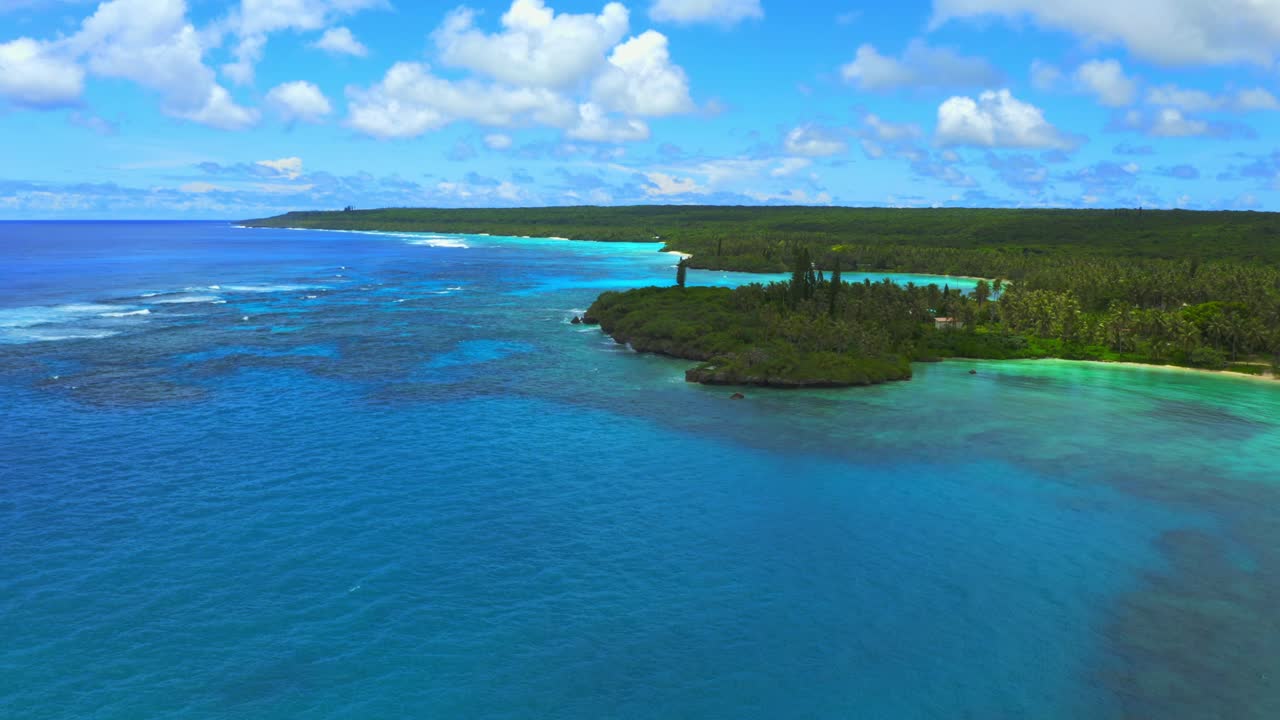 desde el dron captura el paisaje de la costa de la isla lifou, mostrando sus hermosas calas y bahías rodeadas de exuberantes bosques verdes, las aguas cristalinas de un azul profundo del océano pacífico