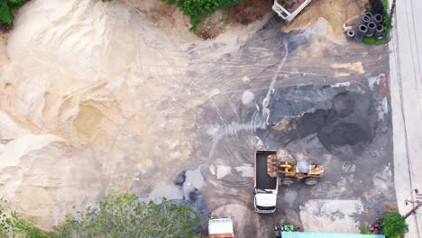 drone over sand quarry with heavy machinery.the truck and excavator.the truck drives up to the excavator for sand and crushed stone loading