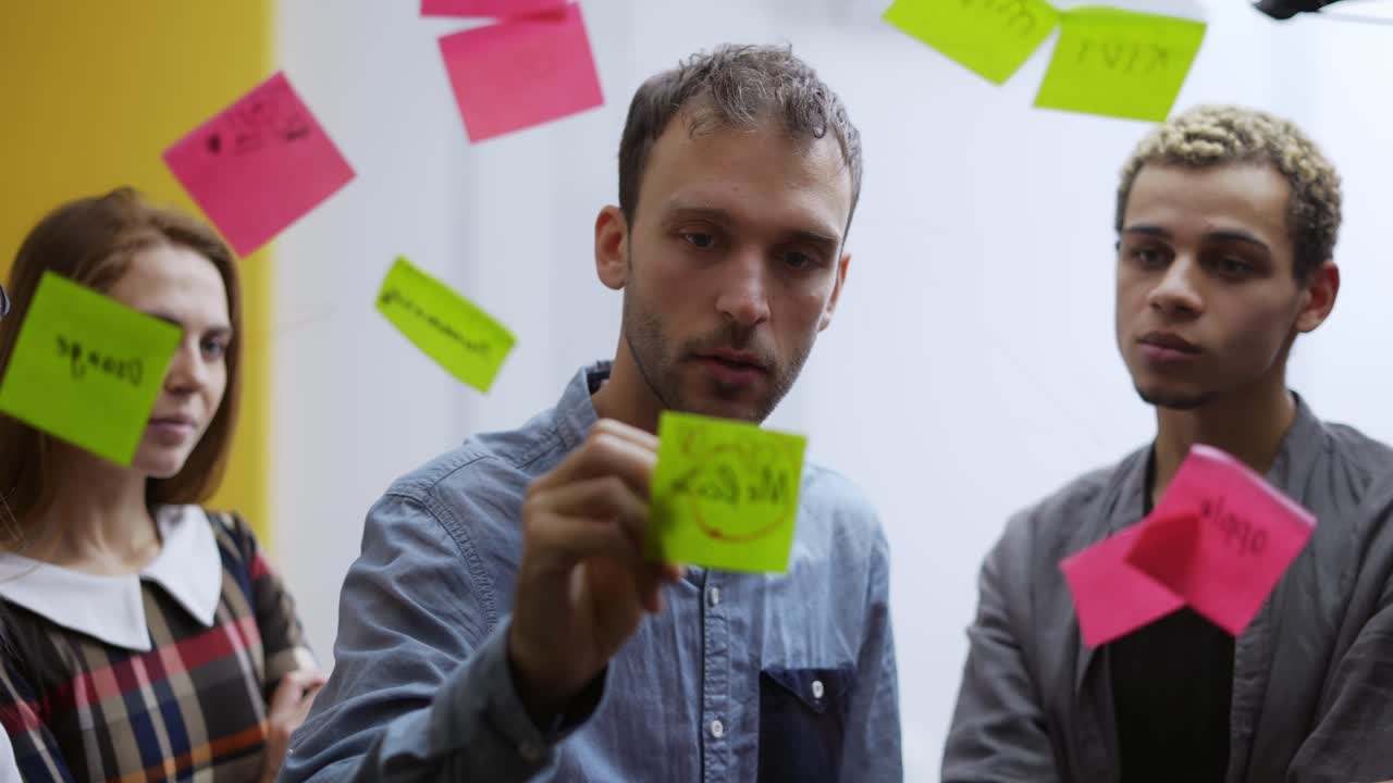 grupo diverso de trabajadores de la oficina de finanzas que tienen capacitación corporativa y utilizan paredes de vidrio con pegatinas