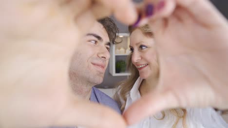 Mother-and-son-making-heart-for-camera.