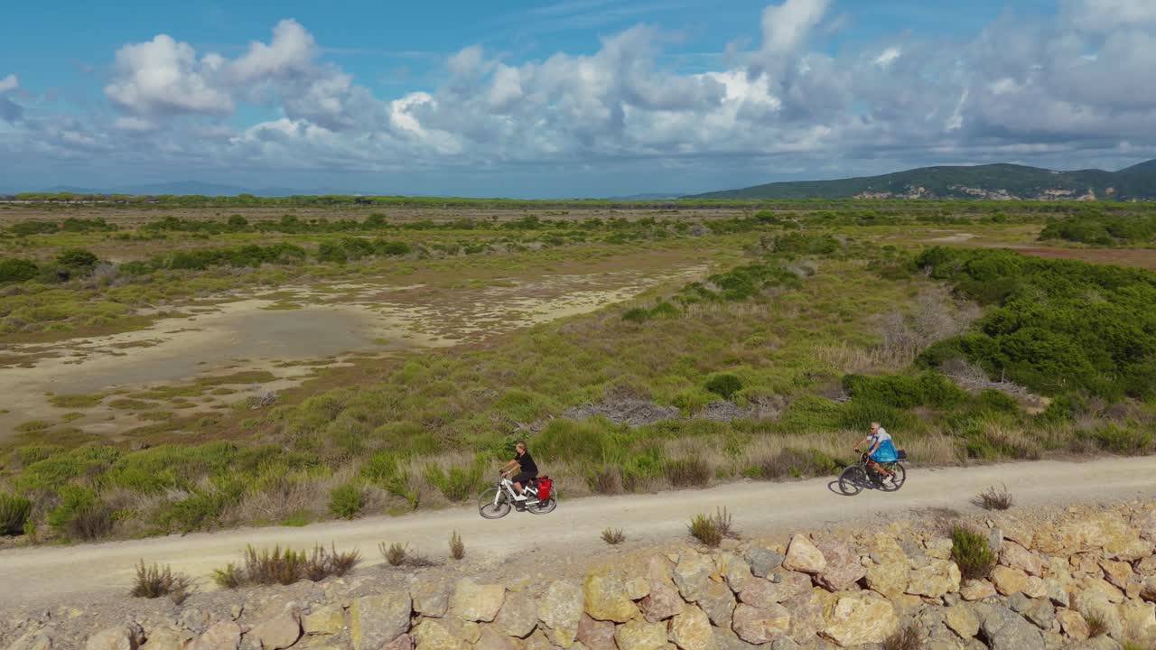 una pareja de ancianos montando bicicletas eléctricas, un recorrido activo y deportivo en italia junto al mar.