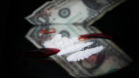 a pile of white cocaine powder with blood stain on black glass turning table against blurry dollar bill