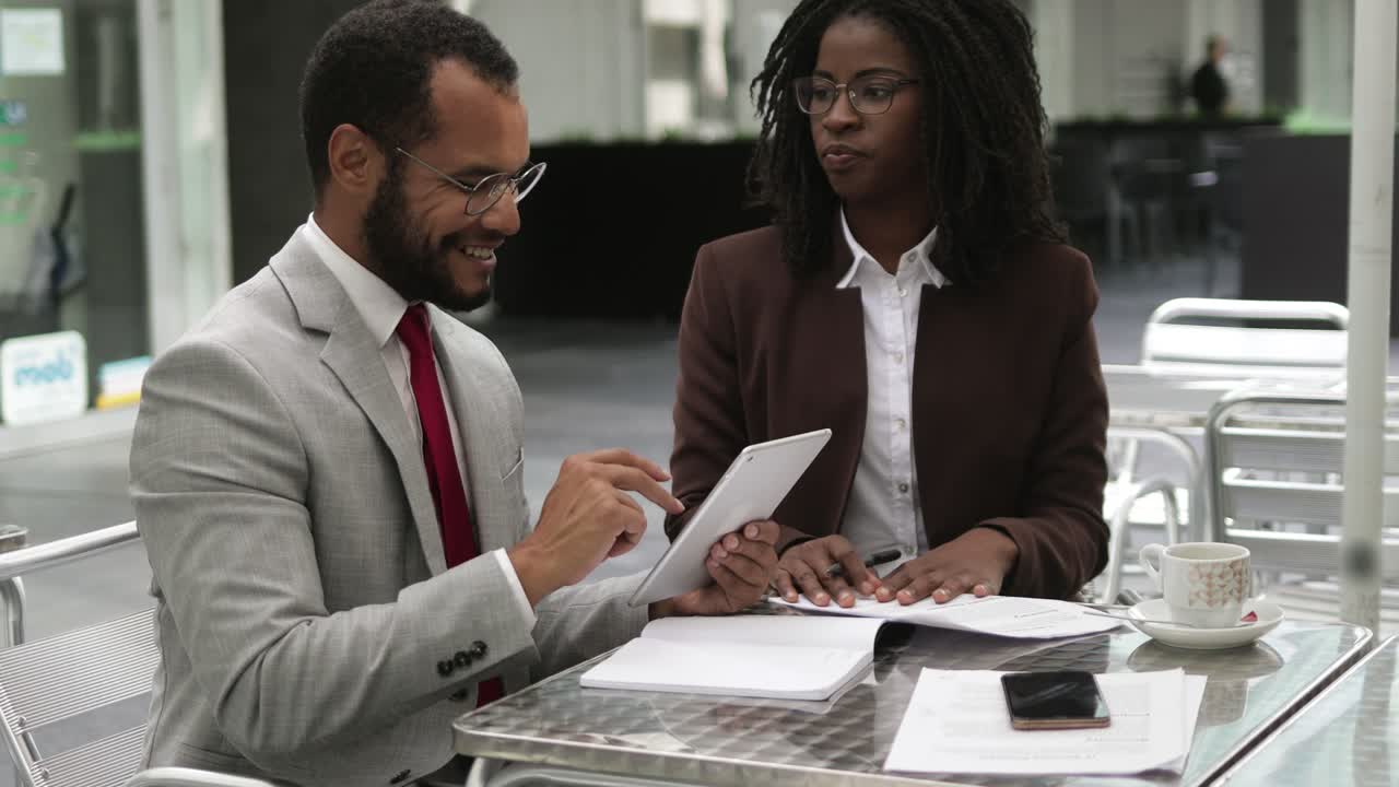 Two business people signing documents at cafe