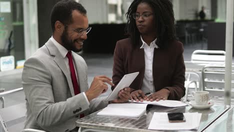 two business people signing documents at cafe