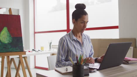 Video-of-biracial-female-designer-working-on-laptop-in-studio